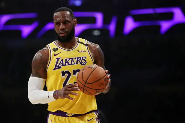 nba news-lebron james in yellow lakers jersey holding the ball in one of the nba game